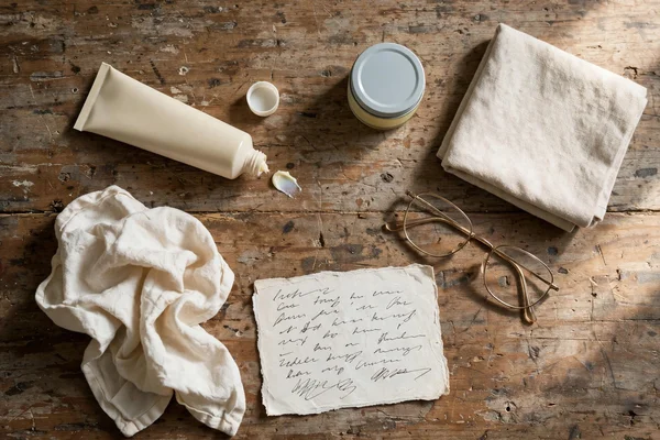 Crema, bálsamo, toalla y anteojos sobre una mesa de madera