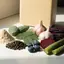 Ingredientes naturales crudos: raíz de yacón en polvo, pencas de nopal, semillas de sacha inchi, hojas de moringa, ajo, arándanos, remolacha, pencas de aloe vera y maíz morado, dispuestos ordenadamente sobre una superficie neutra con un envase genérico de suplementos de fondo.