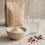 Bodegón editorial con proteína whey en polvo, un vaso de agua y un envase genérico de Cocoa Slim.